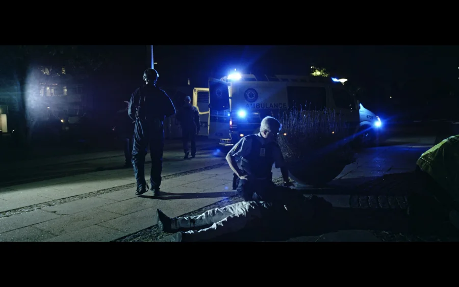 Gadens Melodi — Emergency responders beside an ambulance at night