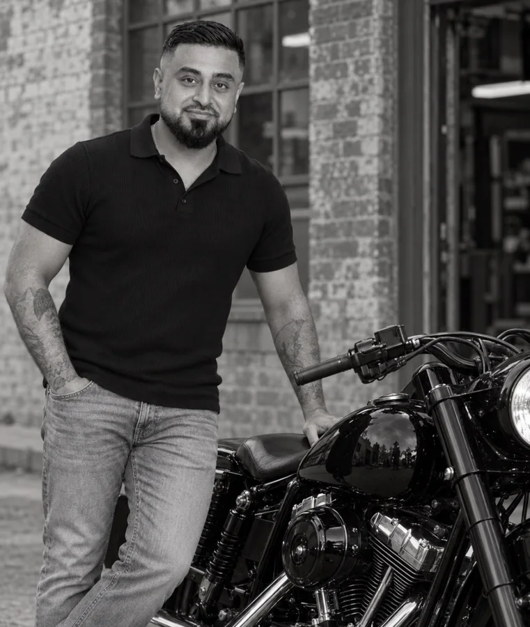 Omid Romal standing beside his Harley-Davidson motorcycle