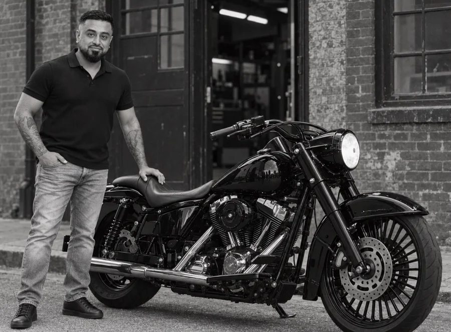 Omid Romal beside a Harley-Davidson outside a workshop