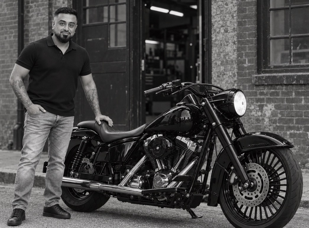 Omid Romal beside his black Harley-Davidson motorcycle outside a brick workshop